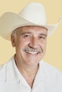 Portrait of happy senior man wearing cowboy hat over yellow background Royalty Free Stock Photo