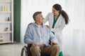 Portrait of happy senior man in wheelchair and his female nurse at retirement home Royalty Free Stock Photo