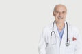Portrait of happy senior medical practitioner over gray background