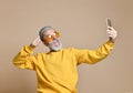 Portrait of happy senior millionaire man using smartphone cellphone make selfie in yellow sunglasses