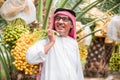 Cheerful old male Arab smiling with yellow dates palm fruit