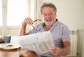 Happy old man reading the newspaper while having breakfast Royalty Free Stock Photo