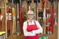 Portrait of a happy senior woman with arms crossed in front of gardening tool