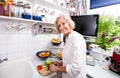 Portrait of happy senior woman chopping fresh vegetables at kitchen counter Royalty Free Stock Photo