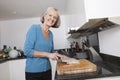 Portrait of happy senior woman chopping vegetables at kitchen counter Royalty Free Stock Photo