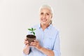 Portrait of happy senior woman, holding pot with green plant, lo Royalty Free Stock Photo