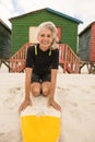 Portrait of happy senior woman kneeling on surfboard at beach Royalty Free Stock Photo