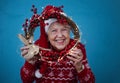 Portrait of happy senior woman with Santa Claus hats in studio, looking trough Christmas wreath. Royalty Free Stock Photo