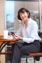 Portrait of happy senior woman sitting at cafe using mobile phone