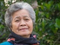 Portrait of a happy senior woman smiling and looking at the camera while standing against trees. Concept of aged people Royalty Free Stock Photo