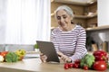 Portrait Of Happy Senior Woman Using Digital Tablet While Cooking In Kitchen Royalty Free Stock Photo