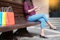 Portrait of a happy shopper paying online with credit card through smartphone with bags in a mall