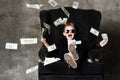 Portrait of happy shouting self-confident rich kid boy millionaire sitting in luxury armchair and throwing money dollars cash Royalty Free Stock Photo