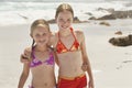 Portrait Of Happy Sisters Standing On Beach