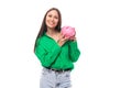 portrait of a happy slim cute brown-eyed brunette woman dressed in a green shirt holding a piggy bank Royalty Free Stock Photo