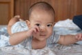 Portrait of happy small Asian infant baby. Kid is lying, smiling, playing on the bed