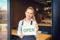 Portrait of happy small business owner standing at restaurant entrance holding open sign Royalty Free Stock Photo