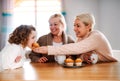 A portrait of small girl with mother and grandmother at the table at home. Royalty Free Stock Photo