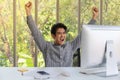 Portrait of happy smart young asian businessman looking to desktop computer and clench two fists and emotion glad in working room