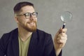 Happy young student or businessman in glasses looking through a magnifying glass Royalty Free Stock Photo