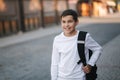 Portrait of happy smiled teenage boy in white sweatshirt with backpack outside Royalty Free Stock Photo