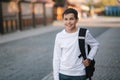 Portrait of happy smiled teenage boy in white sweatshirt with backpack outside Royalty Free Stock Photo