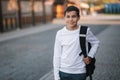 Portrait of happy smiled teenage boy in white sweatshirt with backpack outside Royalty Free Stock Photo