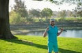 Portrait of happy smilin golfer hitting golf shot with club on course.