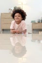 Portrait of happy smiling African boy with black curly hair lying on floor and playing toy in bedroom. Child with reflections on Royalty Free Stock Photo