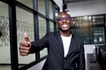 Portrait of happy smiling African businessman in black suit wearing glasses and giving thumb up inside building Royalty Free Stock Photo