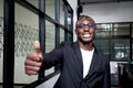 Portrait of happy smiling African businessman in black suit wearing glasses and giving thumb up inside building Royalty Free Stock Photo