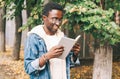 Portrait happy smiling african man reading book in autumn