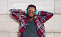 Portrait happy smiling african man with wireless headphones enjoying listening to music in city on gray wall background Royalty Free Stock Photo