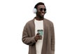 Portrait of happy smiling african man in wireless headphones listening to music with cup of coffee looking away isolated on white Royalty Free Stock Photo