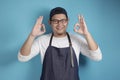 Portrait of happy smiling Asian chef or waiter smiling at camera and shows OK delicious hand gesture Royalty Free Stock Photo