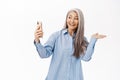 Portrait of happy smiling asian senior woman, old lady showing smth while on video call, talking with mobile phone app Royalty Free Stock Photo