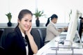 Portrait of happy smiling Asian woman officer sitting at office desk with blurred busy working colleague background, Modern Royalty Free Stock Photo