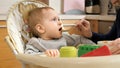 Portrait of happy smiling baby boy getting messy while eating in highchair. Concept of parenting, healthy nutrition and baby Royalty Free Stock Photo