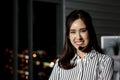 Portrait of happy smiling beautiful Asian woman with headphones work night shift at call center customer care service desk, Royalty Free Stock Photo