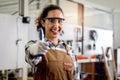 Portrait of happy smiling beautiful carpenter woman wearing safety glasses goggles and apron, giving thumb up to camera, female Royalty Free Stock Photo