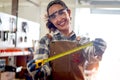 Portrait of happy smiling beautiful carpenter woman wearing safety glasses goggles and apron holding yellow tape measure, female Royalty Free Stock Photo