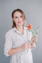 Portrait of happy smiling beautiful middle age Caucasian woman holding red tulip flower. Real woman with short hair at grey light