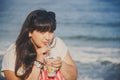 Portrait of happy smiling beautiful overweight young woman in white T-shirt drinking sweet coffee through straw outdoors at beach Royalty Free Stock Photo