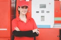 Portrait of happy smiling beautiful woman gas station attendant in red uniform standing with crossed arms at gas station Royalty Free Stock Photo