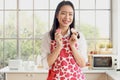 Portrait of happy smiling beautiful young Asian woman in cute red heart apron holding Valentine homemade cookies, standing behind Royalty Free Stock Photo