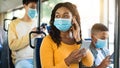 Beautiful smiling black woman in mask listening music in bus Royalty Free Stock Photo