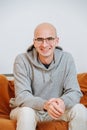 Portrait of a happy smiling happy bold man in glasses sitting on a sofa