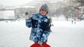 Portrait of a happy smiling boy standing on a snowy hill with his plastic sleds at snowfall before riding down. The concept of Royalty Free Stock Photo