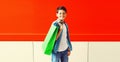 Portrait of happy smiling boy teenager with shopping bag in the city on red background Royalty Free Stock Photo