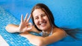 Portrait of happy smiling brunette woman relaxing in swimming pool and showing OK sign with fingers. Royalty Free Stock Photo